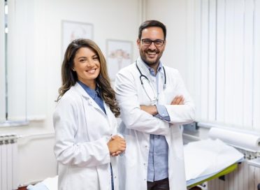 retrato-sonriente-joven-medicos-posicion-juntos-retrato-personal-medico-dentro-moderno-hospital-sonr